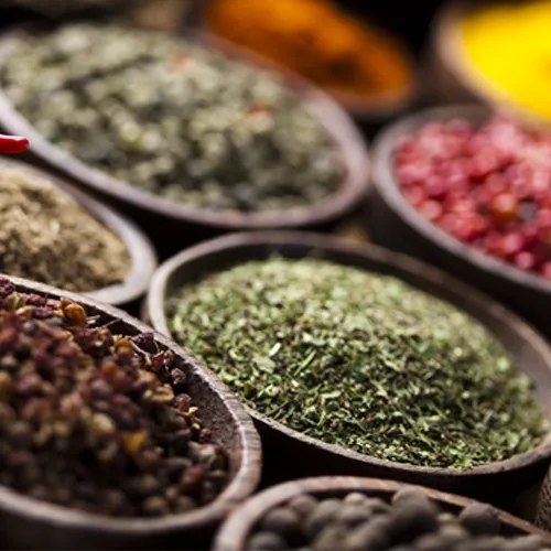 Ground spices and dried herbs in wooden bowls at a market stall